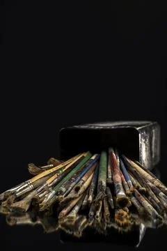 Stack of used paint brushes spilled from artist's metal box. Stock Photos