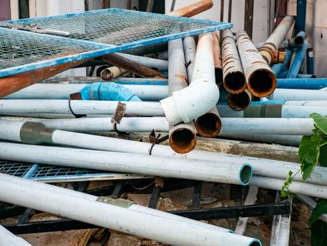 Stack of Used White and Blue PVC Pipes with Rusty Metal Pipes Stock Photos