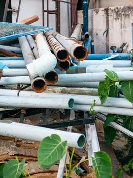 Stack of Used White and Blue PVC Pipes with Rusty Metal Pipes 스톡 사진