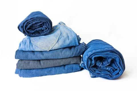 A stack of variety jeans and folded in circle denim trousers beside them look 스톡 사진