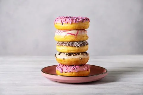 Stack of various colorful donuts on pink ceramic plate Stock Photos