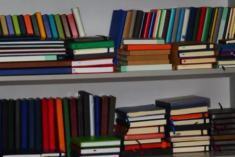Stack of various leather-bound diaries or books in a gray bookcase Stock Photos
