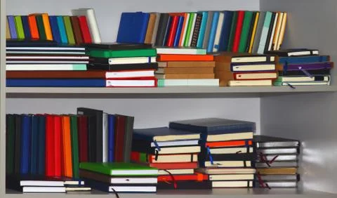 Stack of various leather-bound diaries or books in a gray bookcase Stock-Fotos
