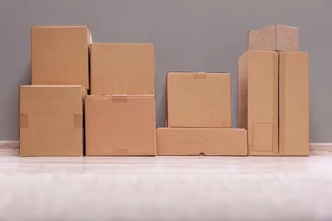 A stack of various-sized, unlabeled brown cardboard boxes sits on a light wooden 写真素材