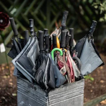 Stack of various umbrellas in a stone container Foto stock