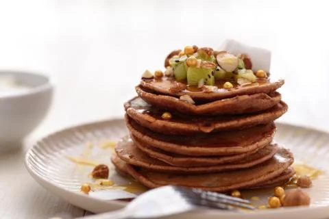 Stack of vegetarian chocolate pancakes with hazelnuts, kiwi, honey on plate Stock Photos