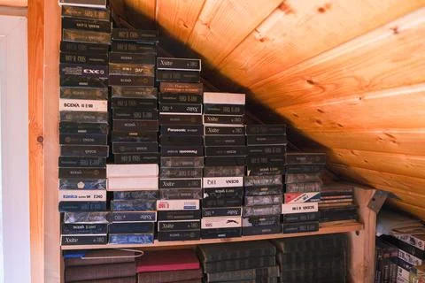 Stack of VHS video cassette tapes and books on rustic wooden shelf, symbolizing Stock Photos
