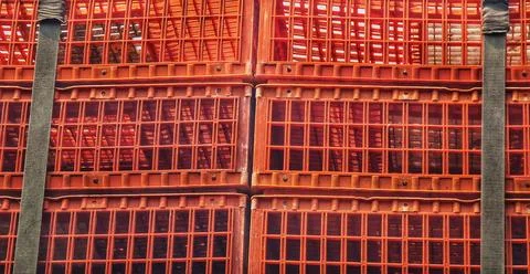 Stack of vibrant orange plastic crates secured with gray strap creates a text Stockfoto's