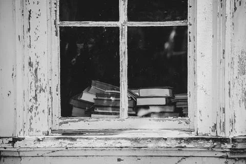 Stack of vintage books seen through window in old house Foto stock
