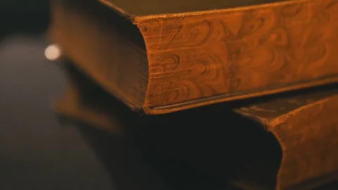 Stack of Vintage Books on Table in Dark Room Moody Light 動画素材 331774351