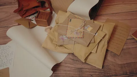 Stack of vintage parcels tied with string on a wooden surface with handwritten 스톡 동영상 296381608