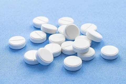 A stack of vitamin and mineral  tablets isolated on a blue background. Stock Photos
