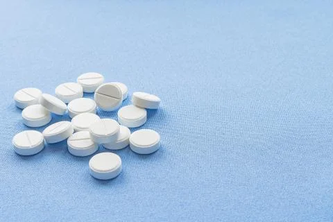 A stack of vitamin and mineral  tablets isolated on a blue background. Stock Photos