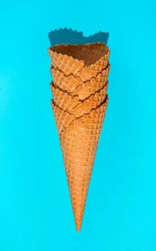 A stack of waffle ice cream cones on a blue background in hard light. Fotos de archivo