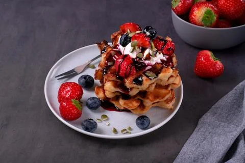 Stack of waffles with berries, whipped cream and chocolate sauce Stock-Fotos