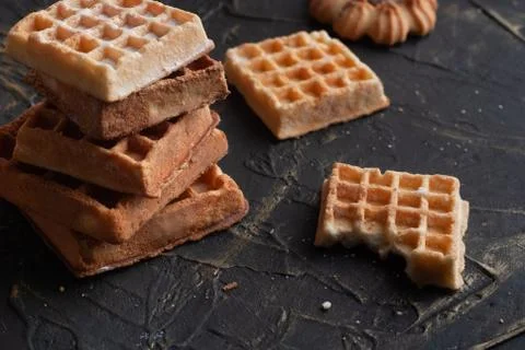 A stack of waffles on a black table, a bitten wafer, Stock Photos