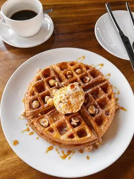 Stack of waffles with a scoop of ice cream, nuts and caramel syrup served wit Stock Photos