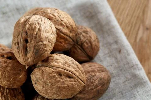 A stack of walnuts piled together and on rustic wooden background, shallow depth Stock Photos