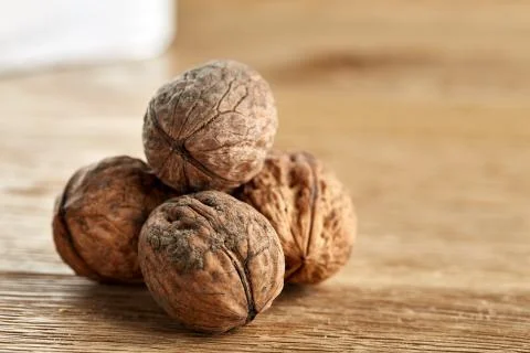 A stack of walnuts piled together and on rustic wooden background, shallow depth Stock Photos