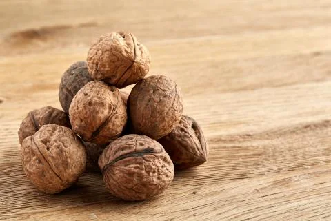 A stack of walnuts piled together and on rustic wooden background, shallow depth Stock Photos