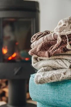 A stack of warm clothes on an armchair an iron fireplace with a Stock Photos