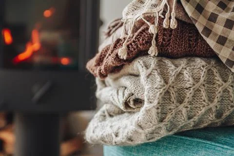 A stack of warm clothes on an armchair an iron fireplace with a Stock Photos