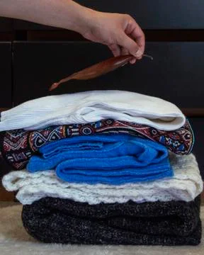 A stack of warm clothes is folded near the dresser Stock Photos