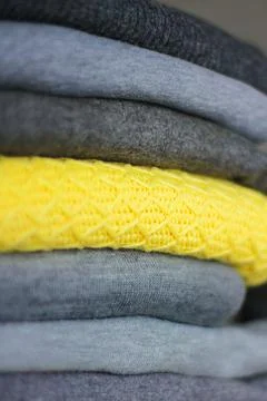 A stack of warm, cozy clothes for winter. among the gray sweaters, one is yel Fotos Stock
