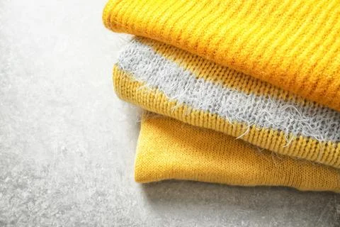 Stack of warm knitted clothes on light background 스톡 사진