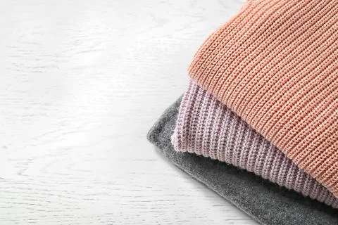 Stack of warm knitted clothes on light background Stock Photos