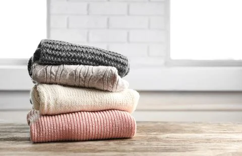 Stack of warm knitted clothes on table 스톡 사진