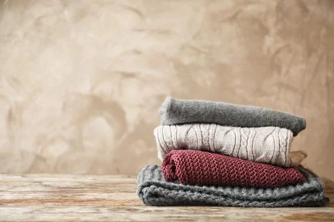 Stack of warm knitted clothes on table 스톡 사진