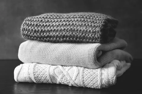 Stack of warm knitted clothes on table Stock Photos
