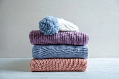 Stack of warm knitted clothes on table Foto stock