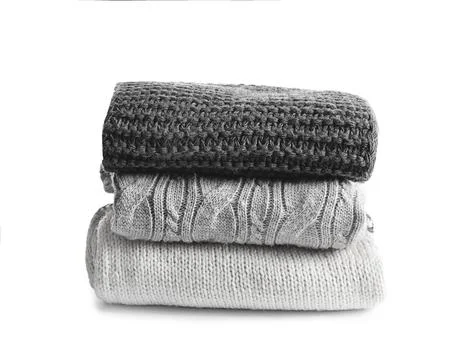 Stack of warm knitted clothes on white background Stock Photos
