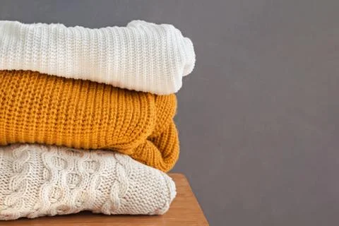 Stack of warm knitted sweaters on the chair Stock Photos