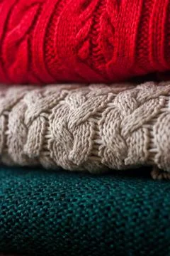 Stack of warm knitted sweaters close up. Cozy colorful background. Stock Photos