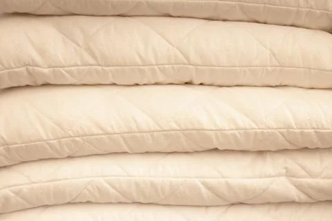 Stack of warm plaid and pillows on white shelf against striped wall backgroun Stock Photos