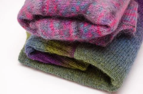 Stack of warm winter knitted sweaters on white background. Stock Photos
