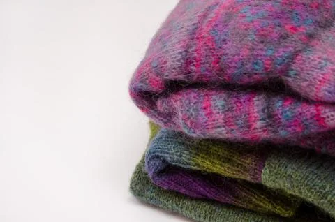Stack of warm winter knitted sweaters on white background. Stock Photos