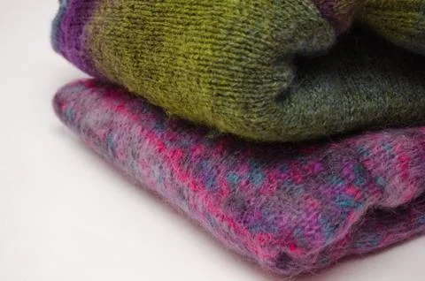 Stack of warm winter knitted sweaters on white background. Stock Photos