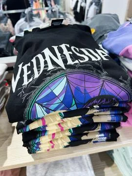 Stack of Wednesday graphic t-shirts displayed on a store shelf Stock Photos