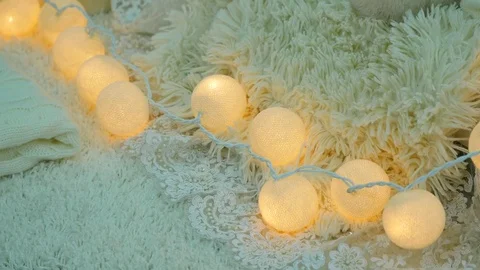 A stack of white and beige pillows and blankets with string lights on vintage Stock Footage 72942018