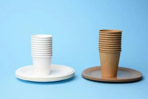 Stack of white and brown paper cups and round plates on a blue background Stockfoto's