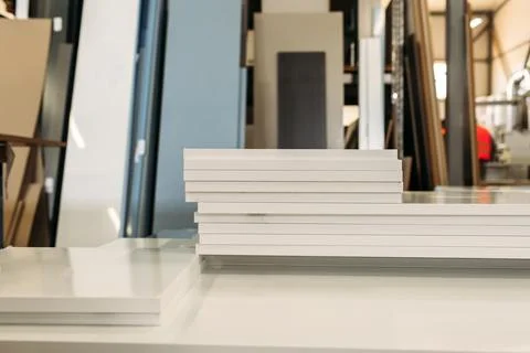 A stack of white cabinet doors sits on a table in a furniture production faci Stock Photos