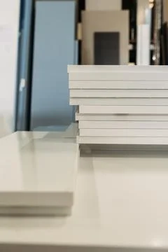 A stack of white cabinet doors sits on a table in a furniture production faci Stock Photos