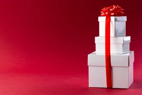 Stack of white christmas presents with red ribbon and copy space on red Stock Photos