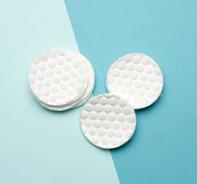 Stack of white cotton round discs for cosmetic procedures on a blue backgr... Stock Photos