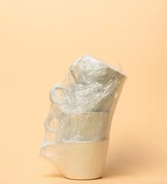 Stack of white cups wrapped in transparent stretch film for moving on a bei.. Stock Photos