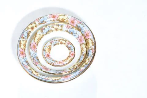 Stack white dinner plates and saucers with flowers and wavy rim top view isol Stock Photos